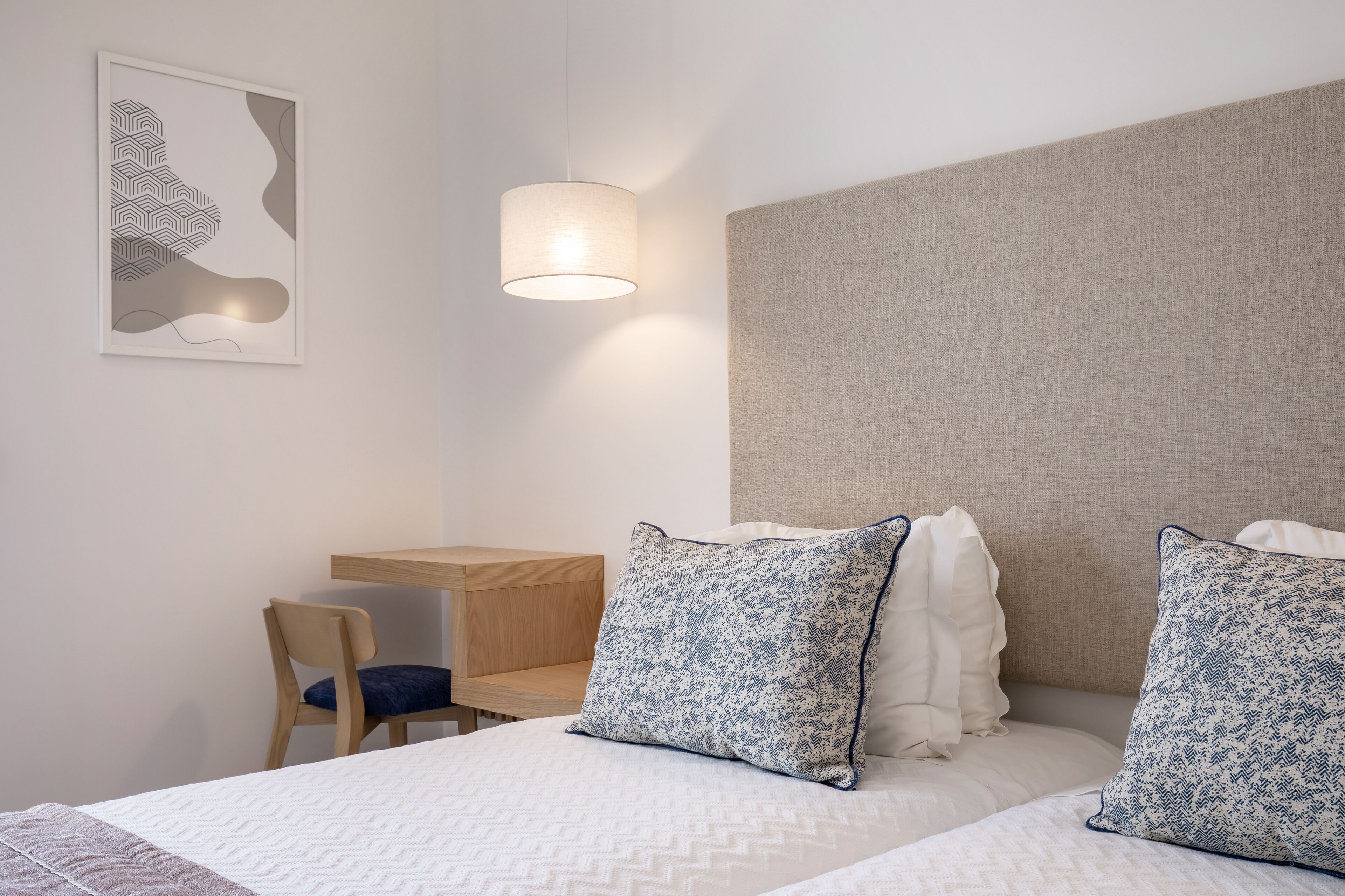 A hotel room with a bed, a desk, and a chair.
