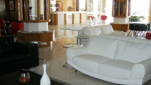 Un moderno vestíbulo de hotel con un sofá blanco, una mesita redonda y una zona de bar al fondo.