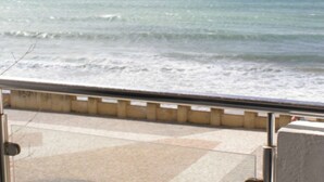Vista del mar desde un balcón con piso de baldosas y baranda metálica.