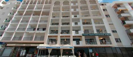 A multi-story hotel with balconies, a ground-level restaurant, and outdoor seating.