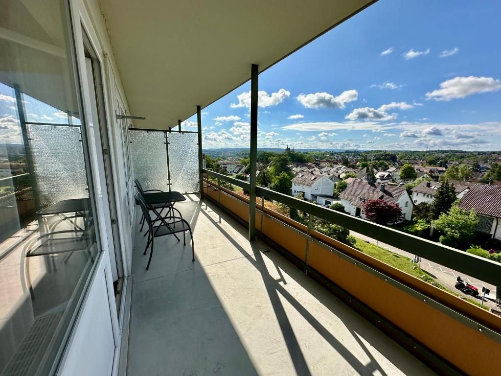Ein Balkon mit Blick auf eine Stadt, ein Stuhl und ein Tisch.