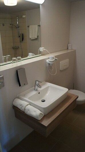 Sink, mirror, and shower area are conveniently located in this bathroom.