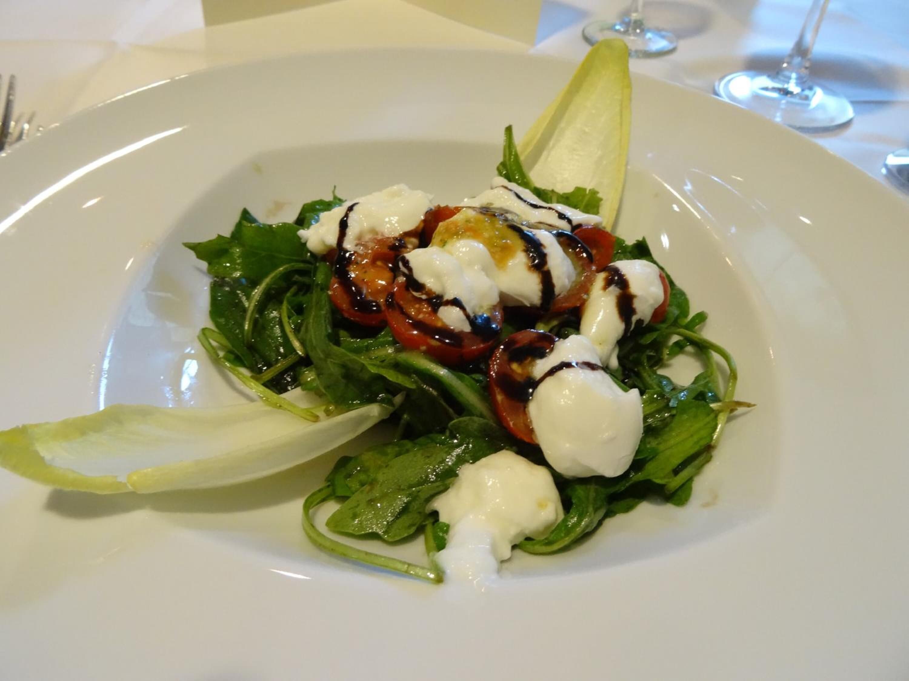 A plate of food with a salad, tomatoes, and a creamy sauce.