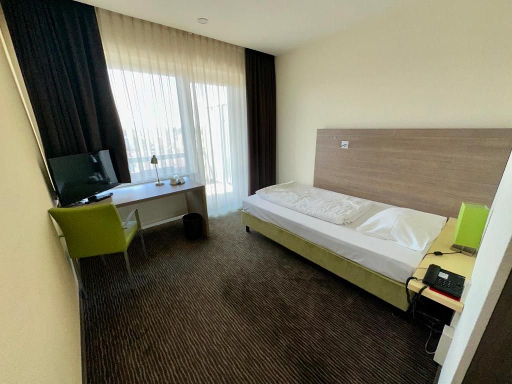 Une chambre d’hôtel équipée d’un lit, d’un bureau, d’une chaise et d’un téléviseur.