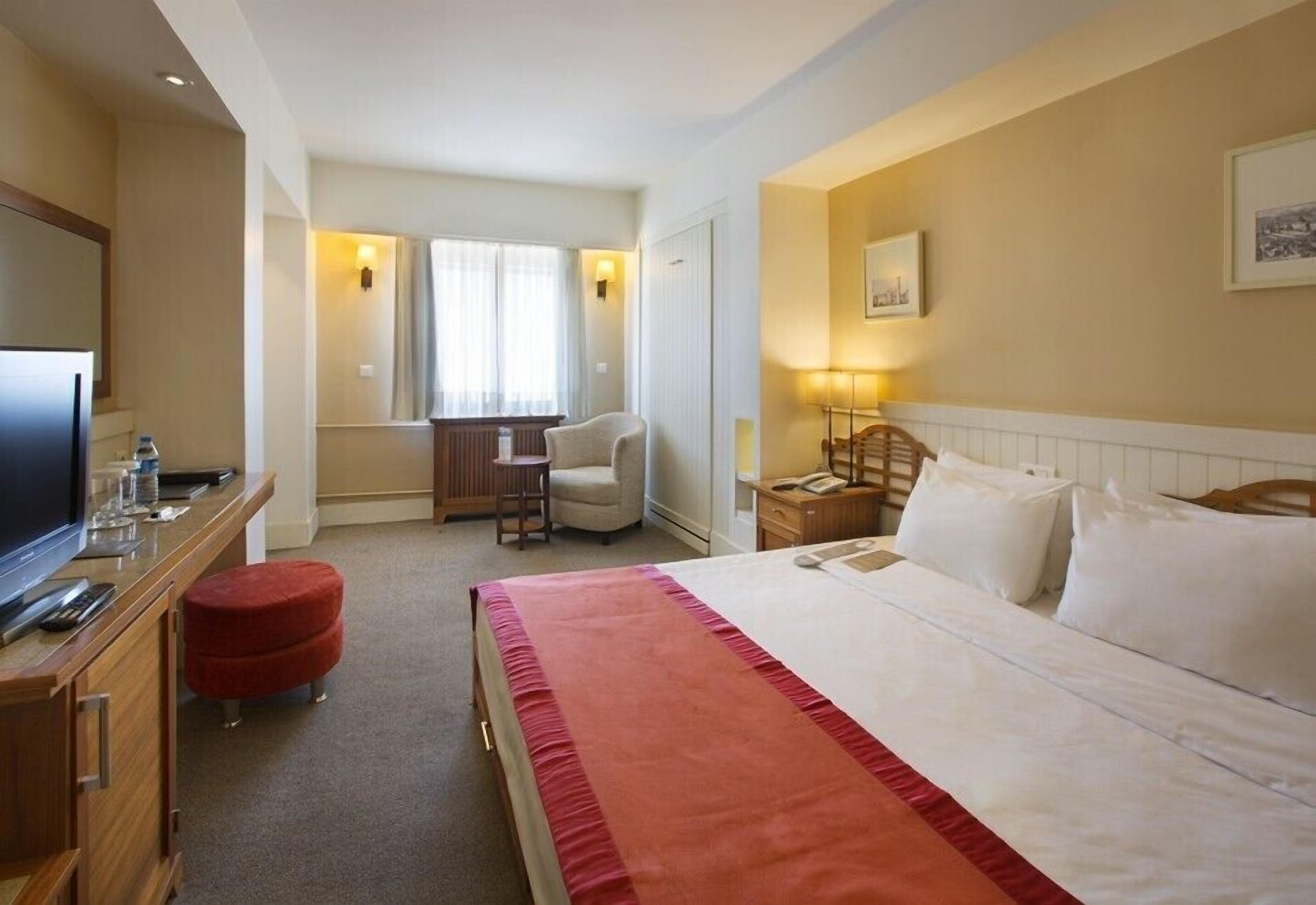 A hotel room with a bed, a desk, a television, and a chair.