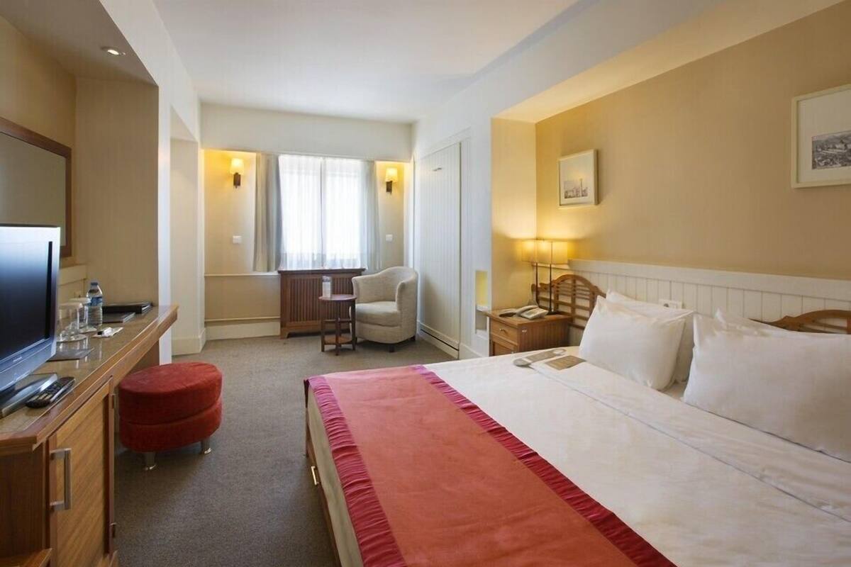 A hotel room with a bed, a desk, a television, and a chair.