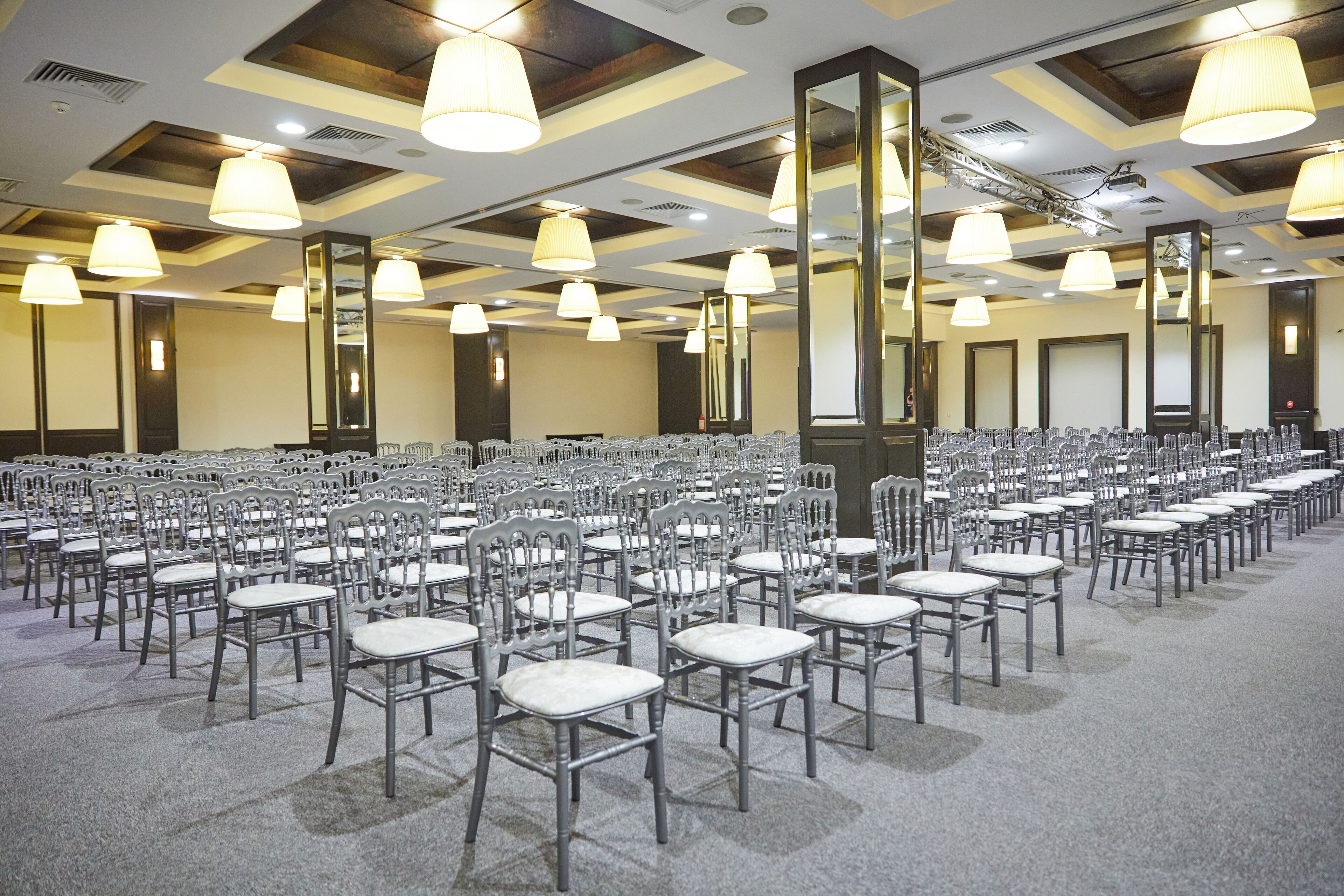 A conference room with rows of chairs, large mirrors, and ceiling lights.