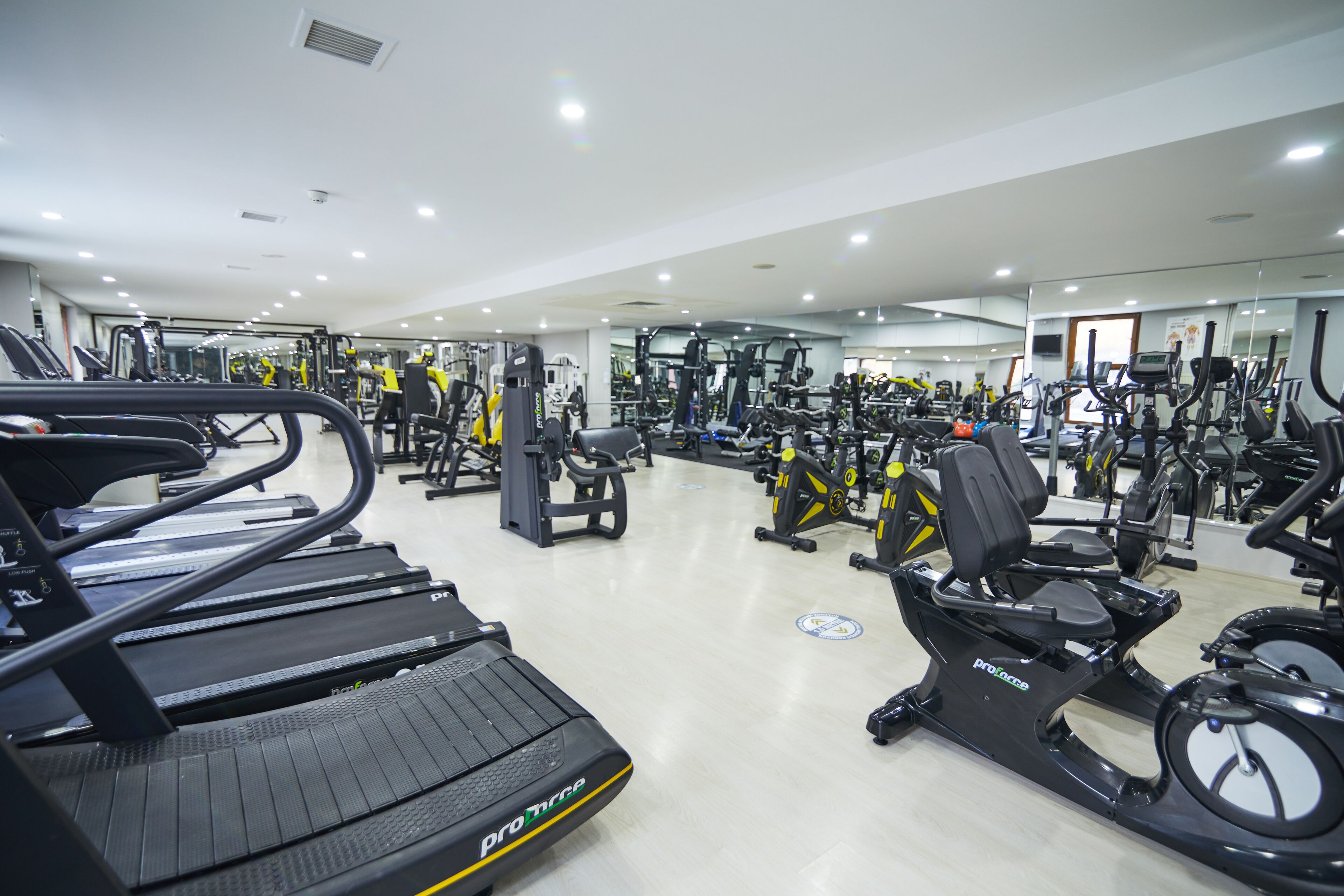 Ein Fitnessstudio mit Laufbändern, Crosstrainern und Kraftgeräten.