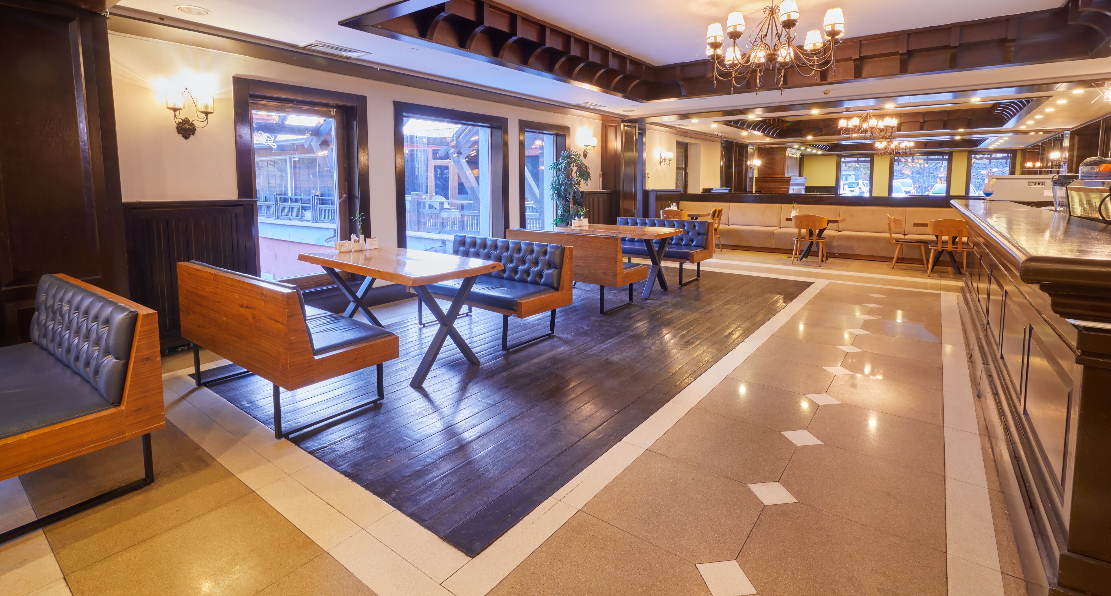 A restaurant with wooden tables and benches, a bar area, and large windows offering views.