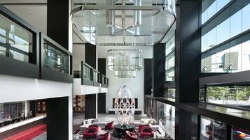 A modern interior with a central glass sculpture, multiple levels with glass railings, and a red carpeted area.