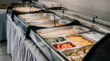 A buffet with various food items including sliced fruits, vegetables, and meats.