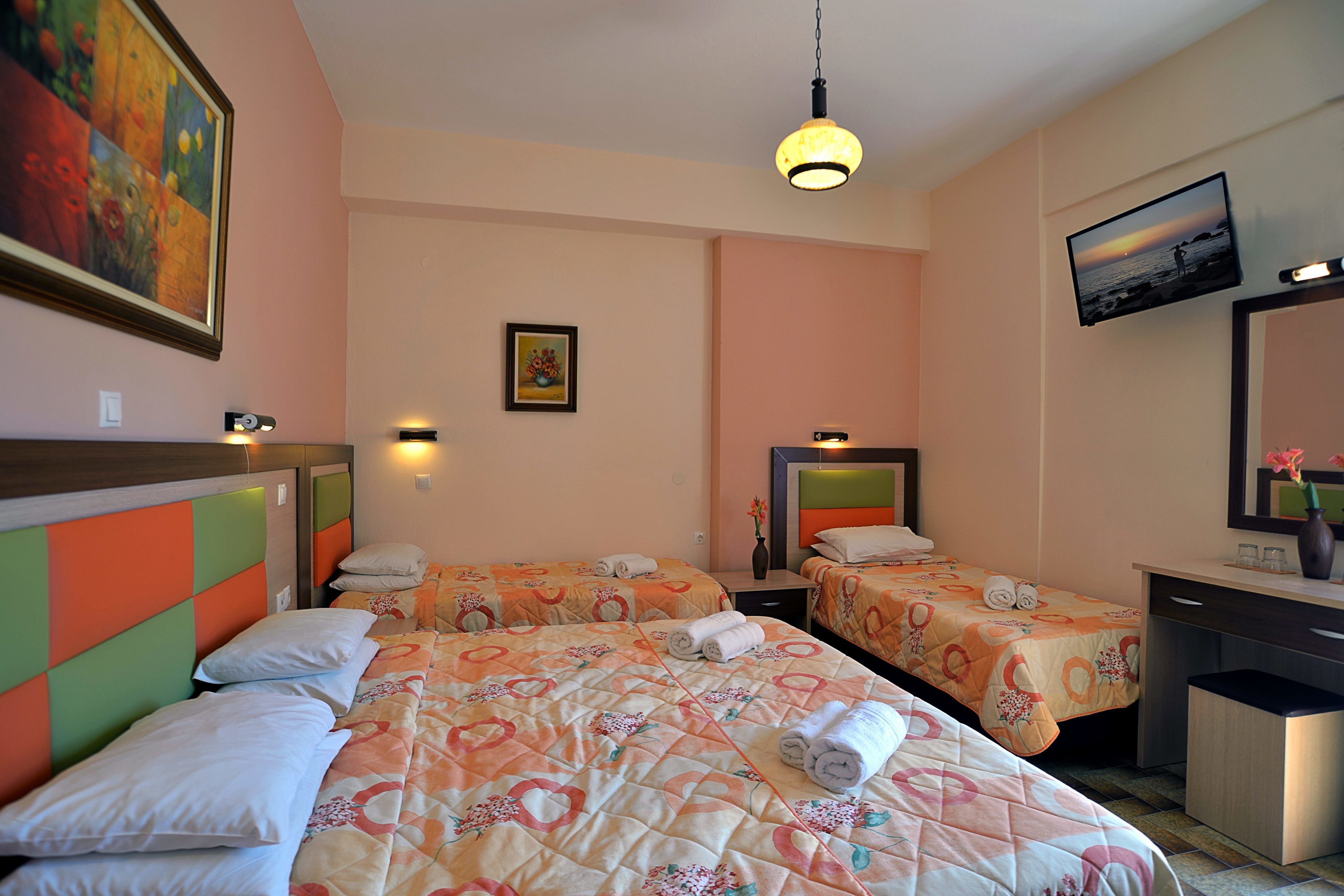 A hotel room with two beds, a desk, a chair, a TV, and a painting on the wall.