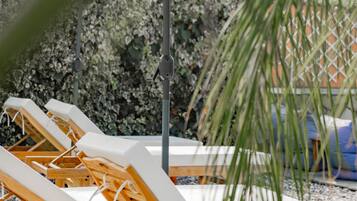Zona de piscina con sillas de descanso y una sombrilla grande.