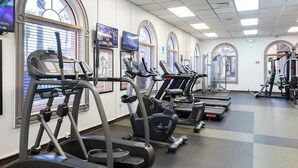 Un gimnasio con cintas de correr, elípticas y equipo de pesas.