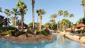 Una piscina rodeada de palmeras y rocas, con un letrero que indica una profundidad de 3 pies.