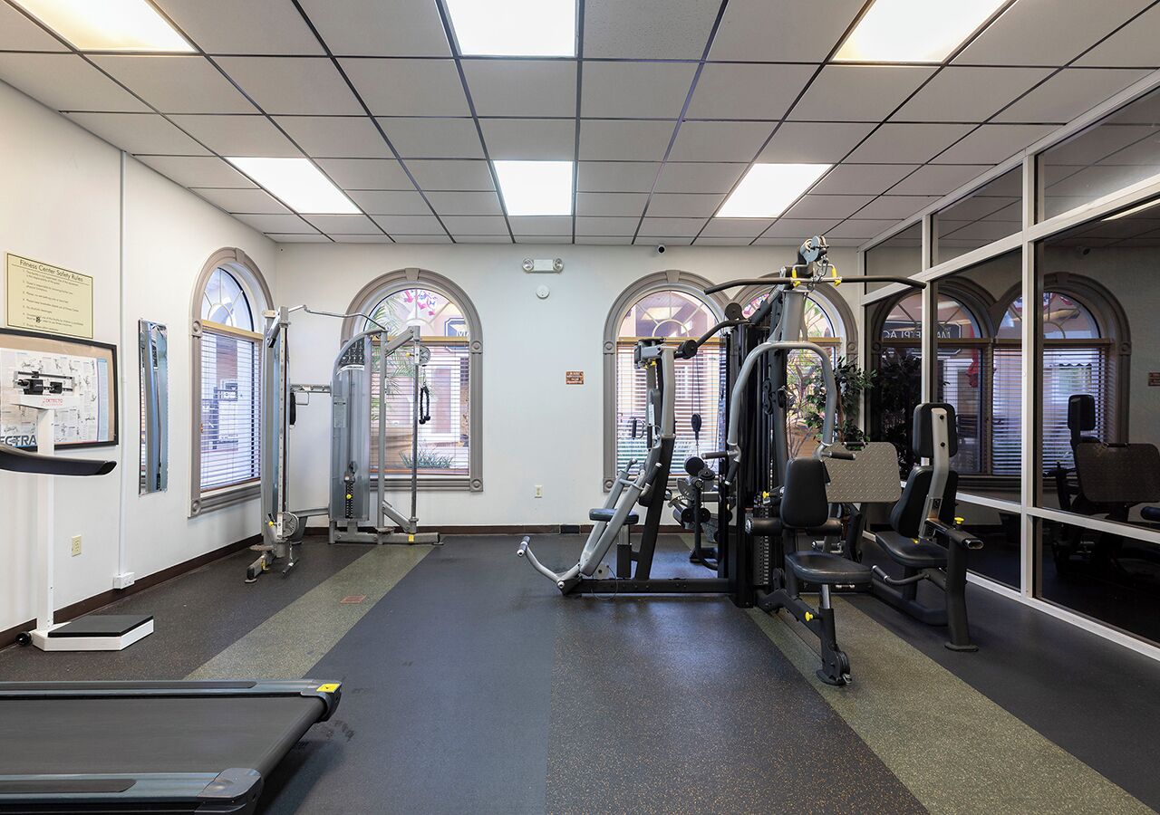 A gym with treadmills, weight machines, and a mirrored wall.