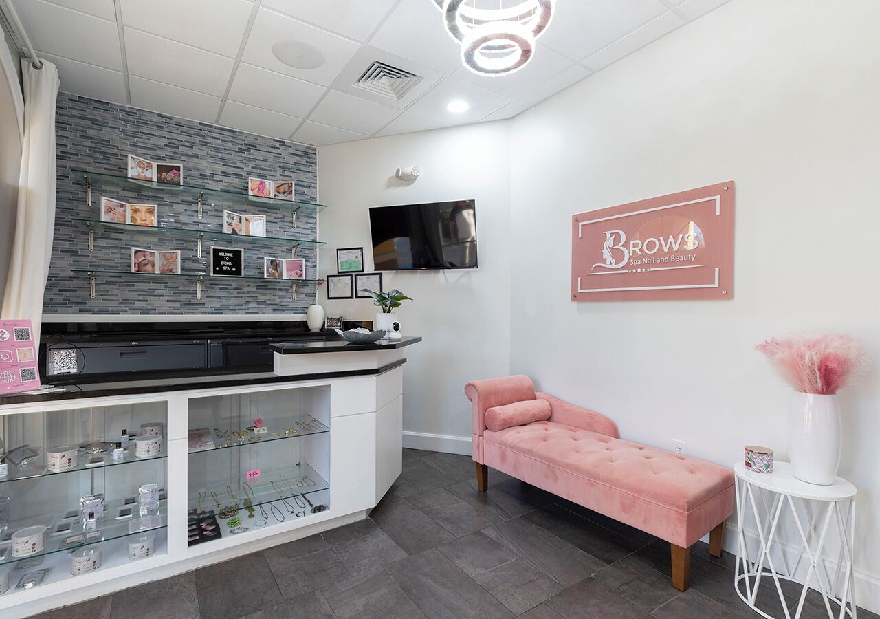 Ein Salon-Interieur mit einer Rezeption, einem rosa Sofa und einem an der Wand befestigten Schild.
