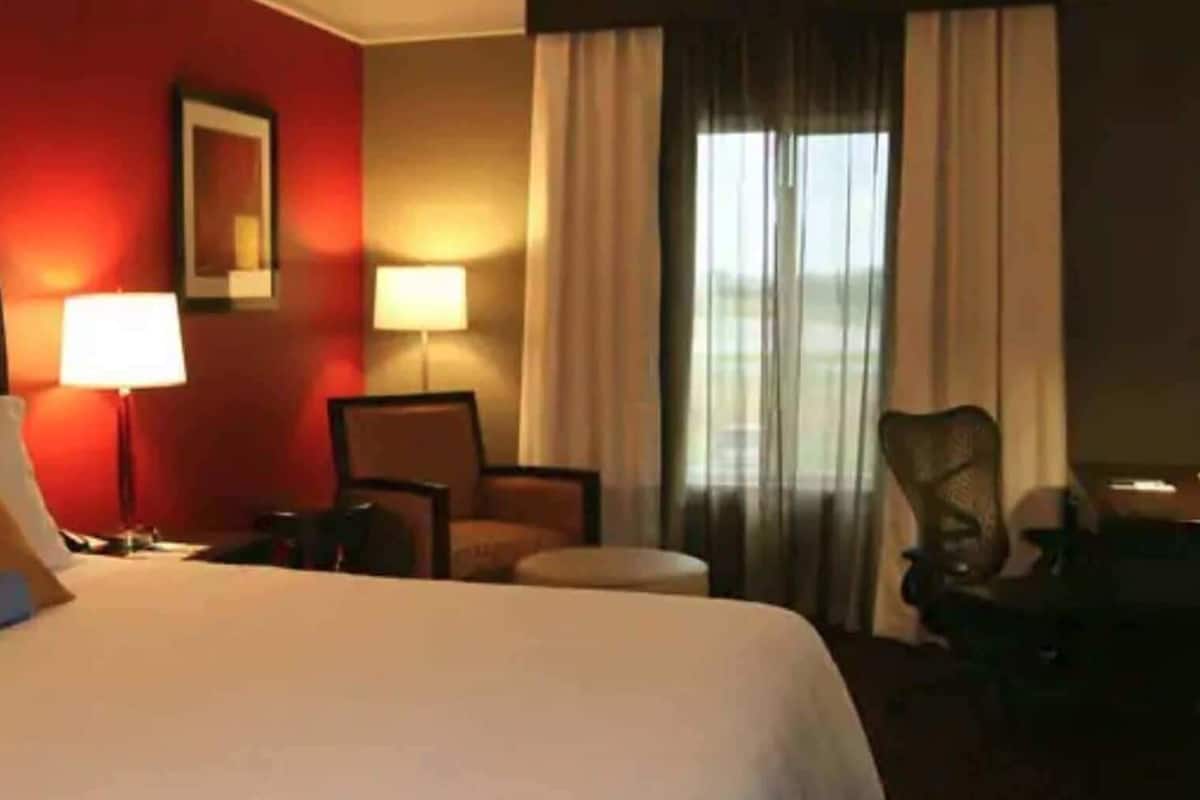 Una habitación de hotel con una cama grande, un escritorio, una silla y una lámpara.