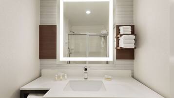A modern bathroom with a large mirror, white sink, and a towel rack with folded towels.