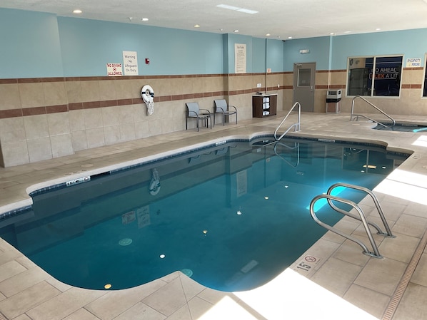 Una piscina interior con agua cristalina, una silla de salvavidas y un letrero que indica que no se permite bucear.