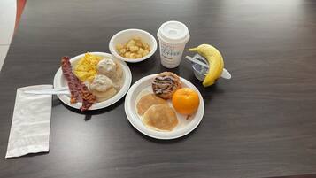 A table with breakfast items including eggs, sausage, biscuits, a banana, and a coffee cup.