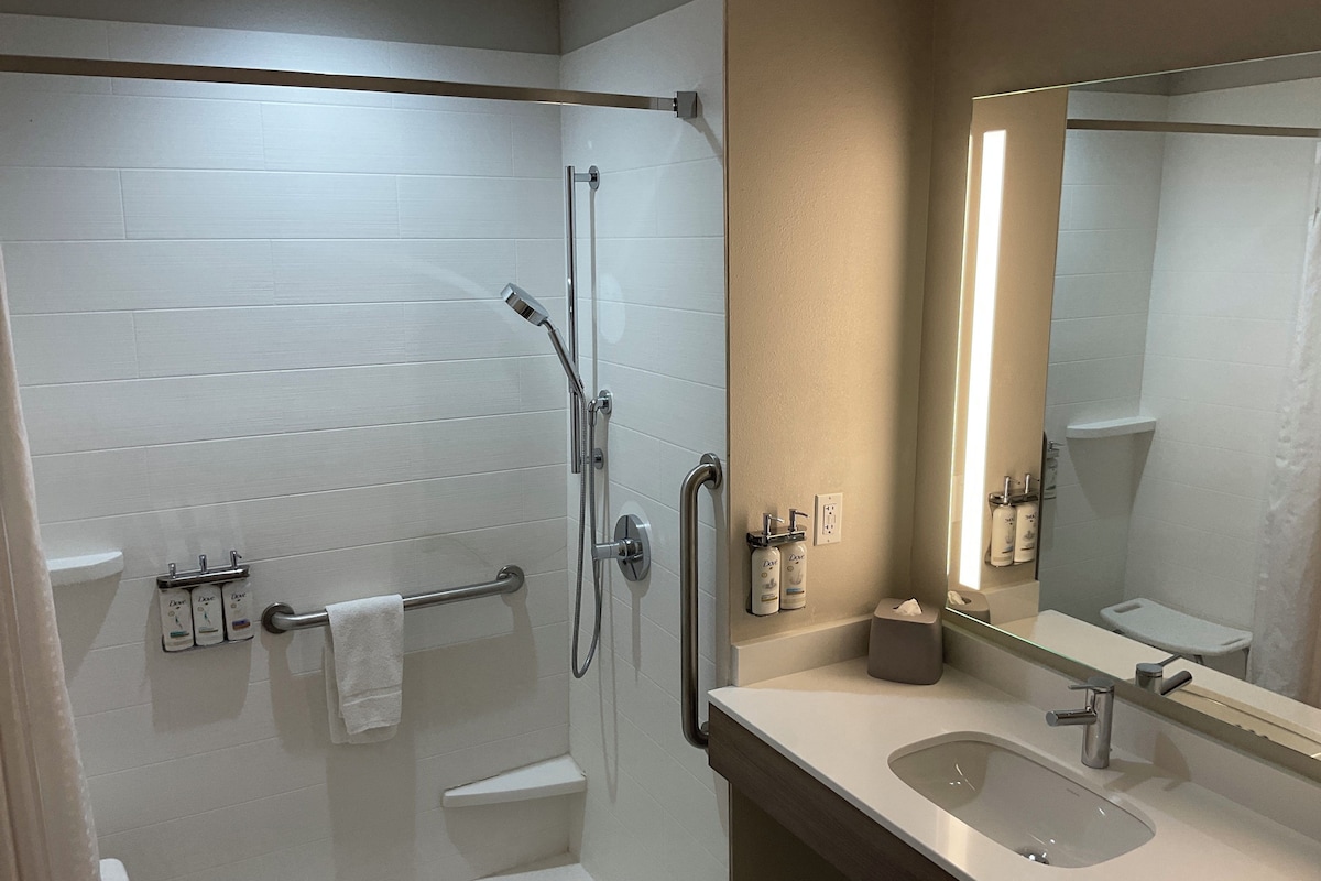 A modern bathroom with a walk-in shower, a vanity with a sink, and a large mirror.