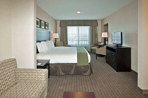A hotel room with a bed, a desk, a television, a chair, and a window with curtains. - Holiday Inn Express Hotel & Suites Grants - Milan by IHG (Grants)