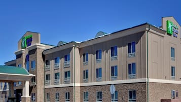A Holiday Inn Express & Suites building with a stone facade, multiple windows, and a green roof.