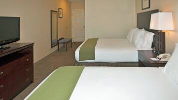 Habitación de hotel con dos camas, televisor, escritorio con teléfono y espejo.