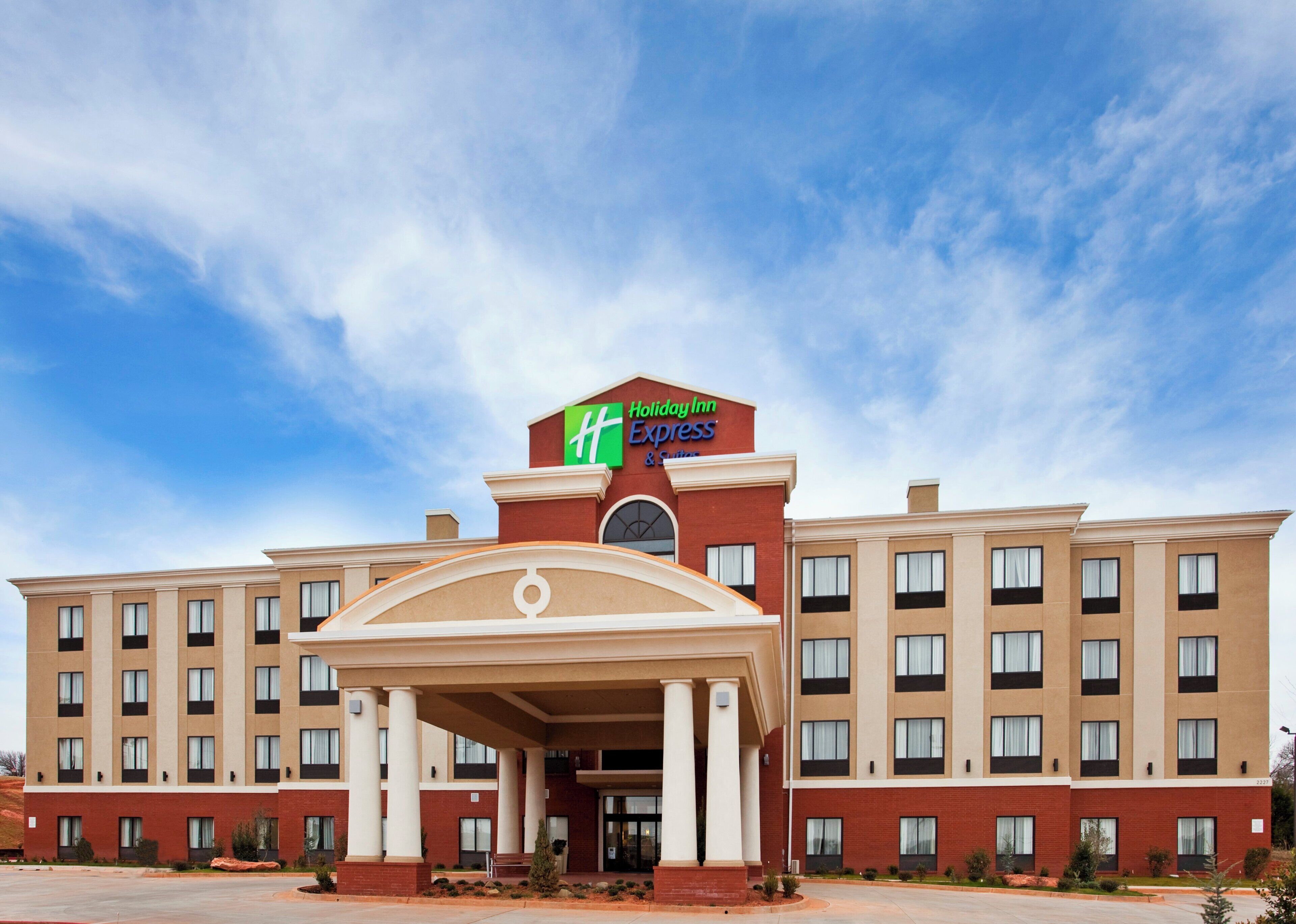 A Holiday Inn Express building with a central entrance, multiple floors, and a clear sky.