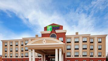 A Holiday Inn Express building with a central entrance, multiple floors, and a clear sky.