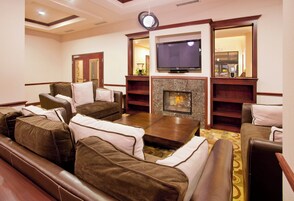 A hotel lounge with leather sofas, a flat-screen TV, and a fireplace.
