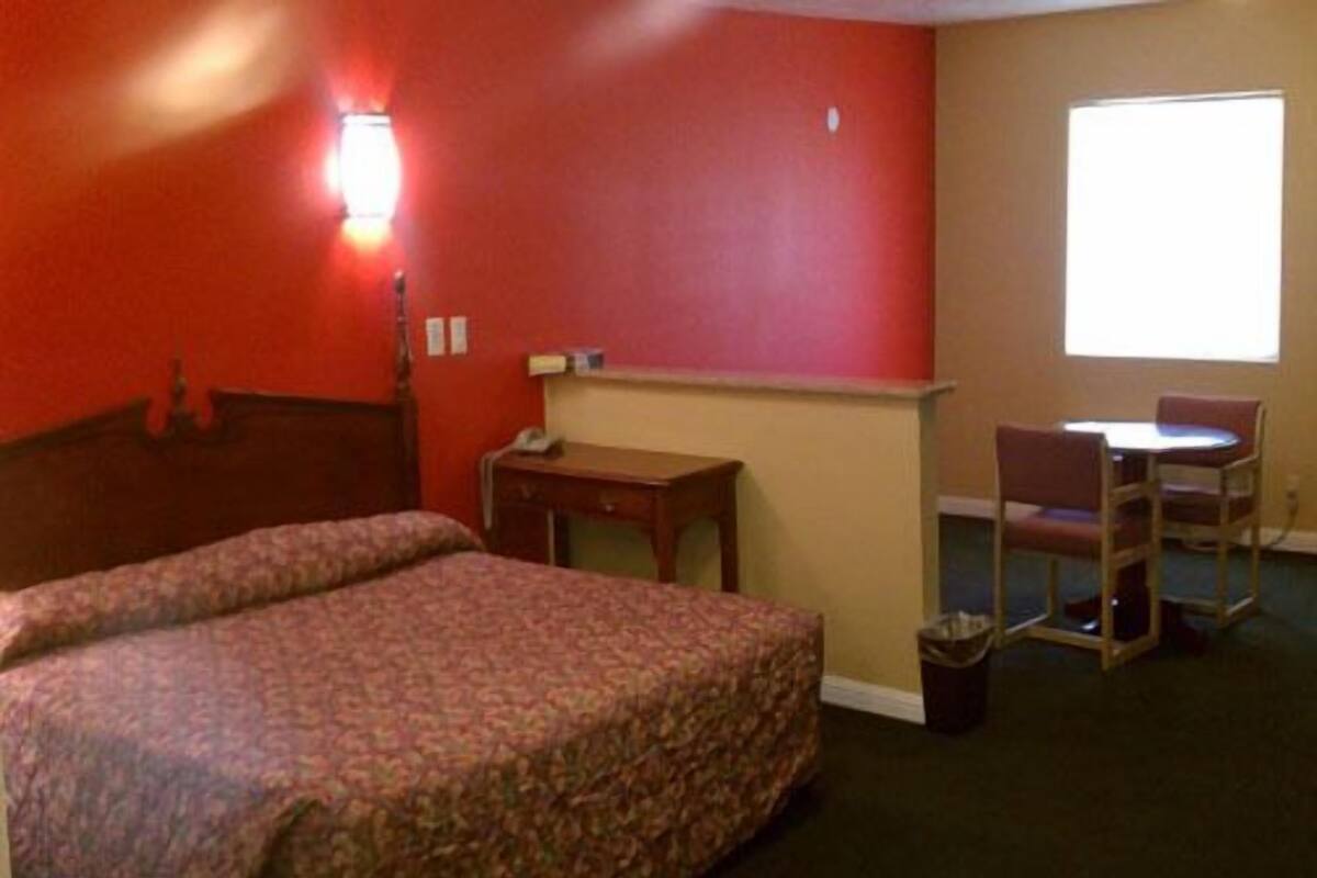 Une chambre d’hôtel avec un lit, un bureau, une chaise et une fenêtre.