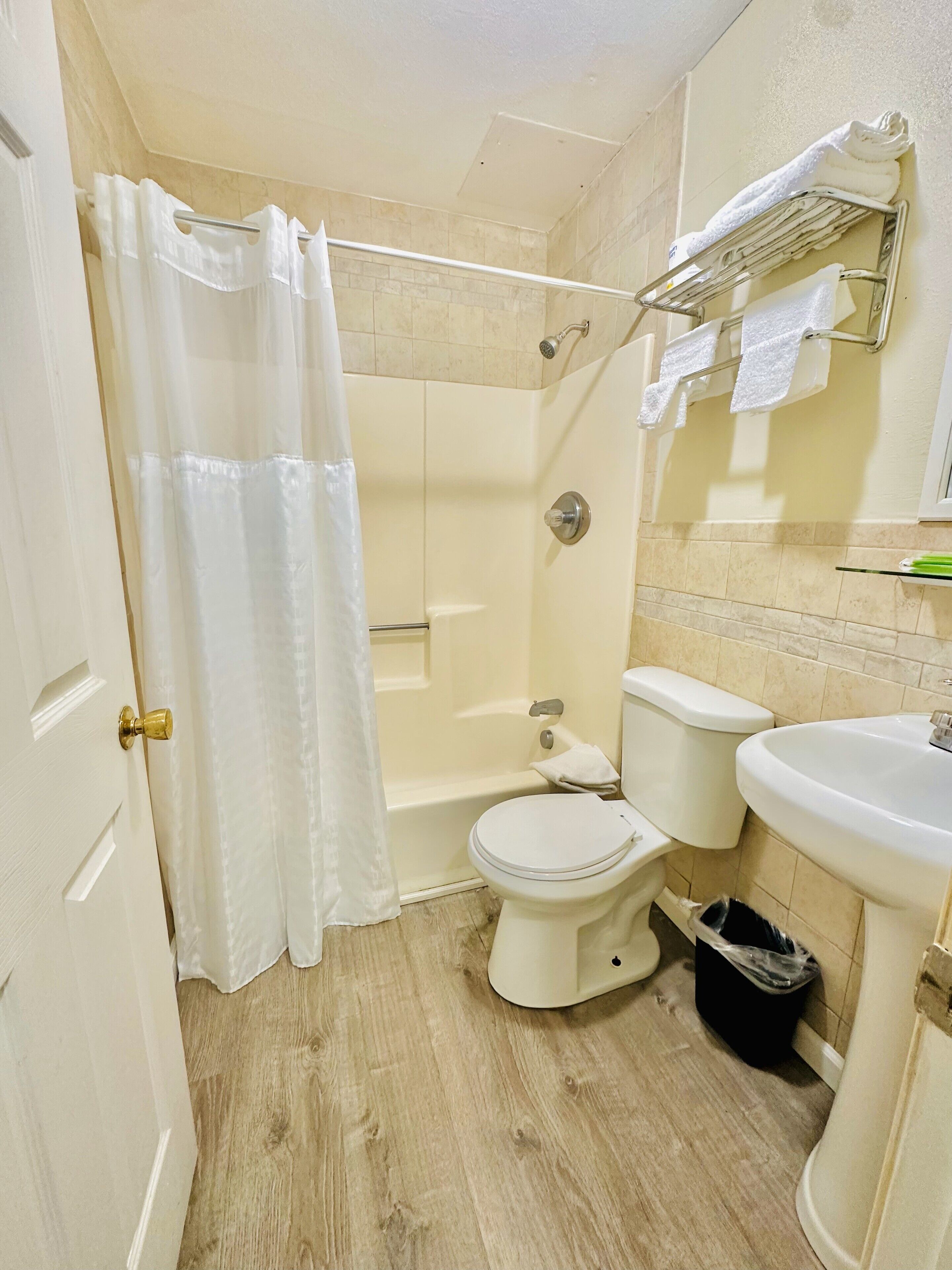 A bathroom with a toilet, sink, shower, and a towel rack.