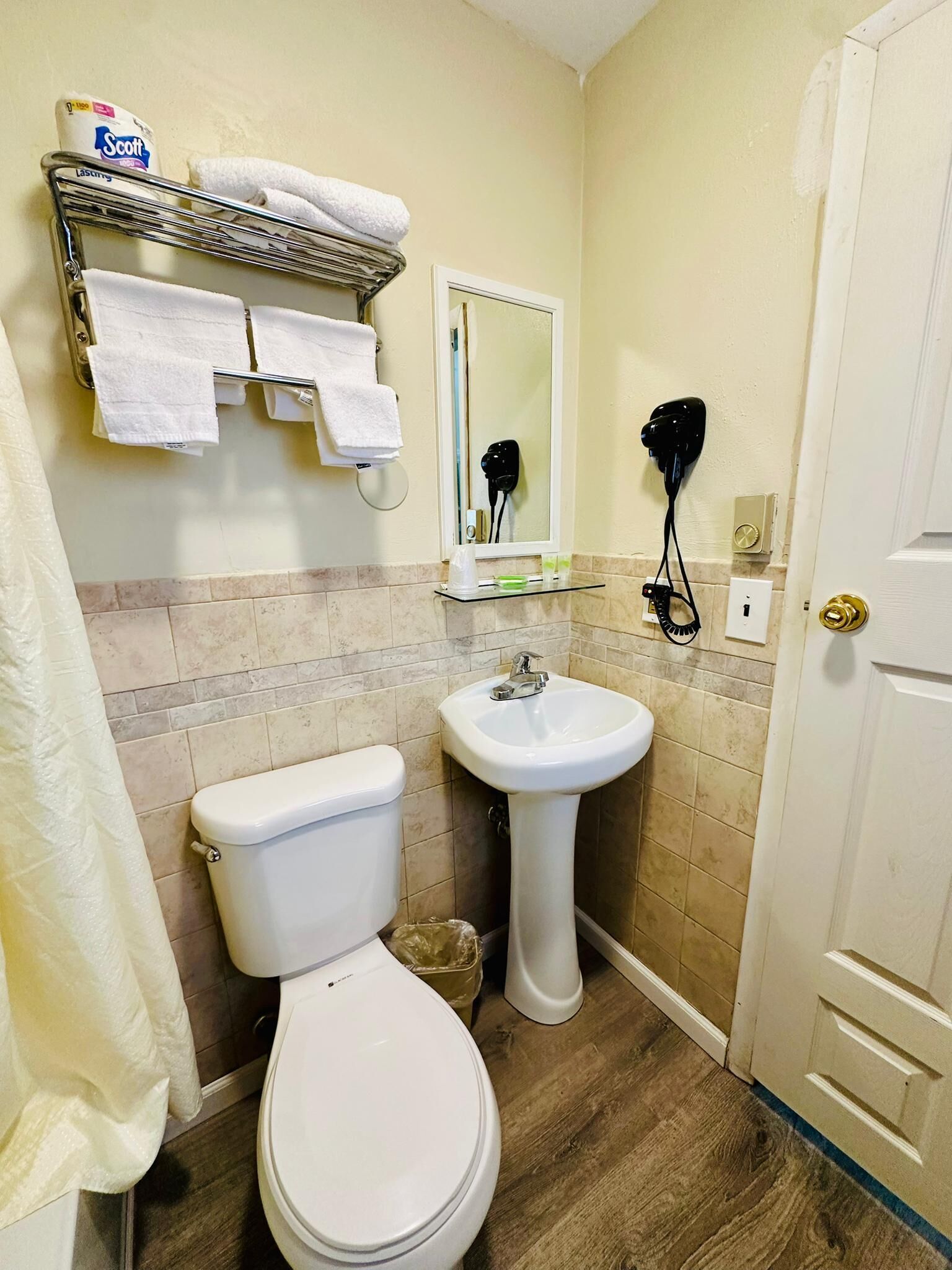 Un baño con inodoro, lavamanos y perchero para toallas.