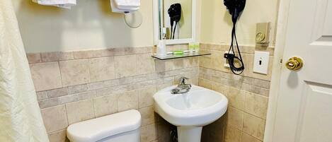 Un baño con inodoro, lavamanos y perchero para toallas.