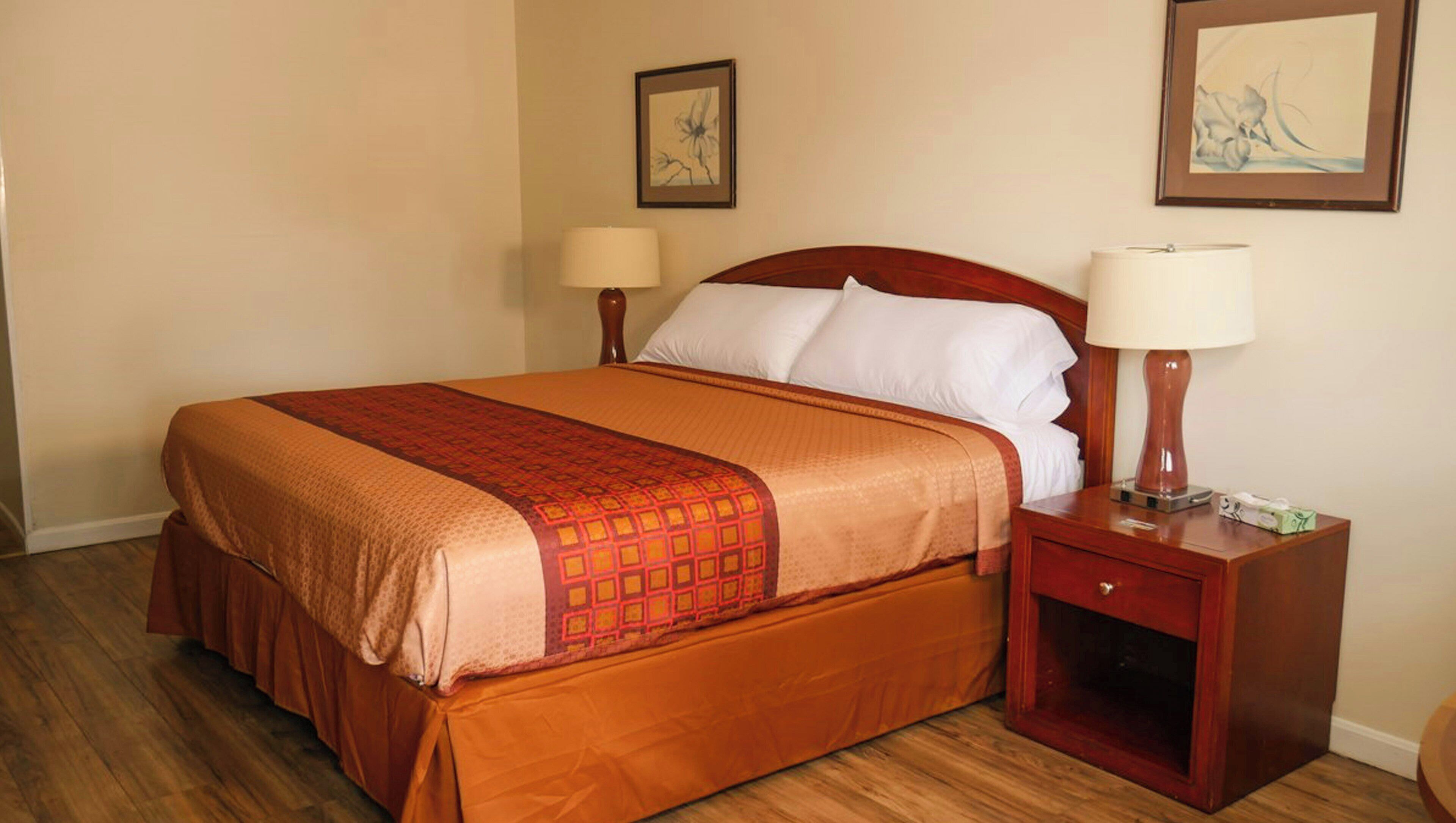 A hotel room with a large bed, two bedside tables, and two wall-mounted lamps.