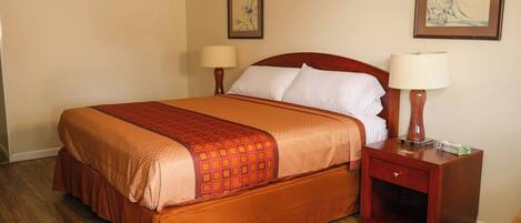 A hotel room with a large bed, two bedside tables, and two wall-mounted lamps.