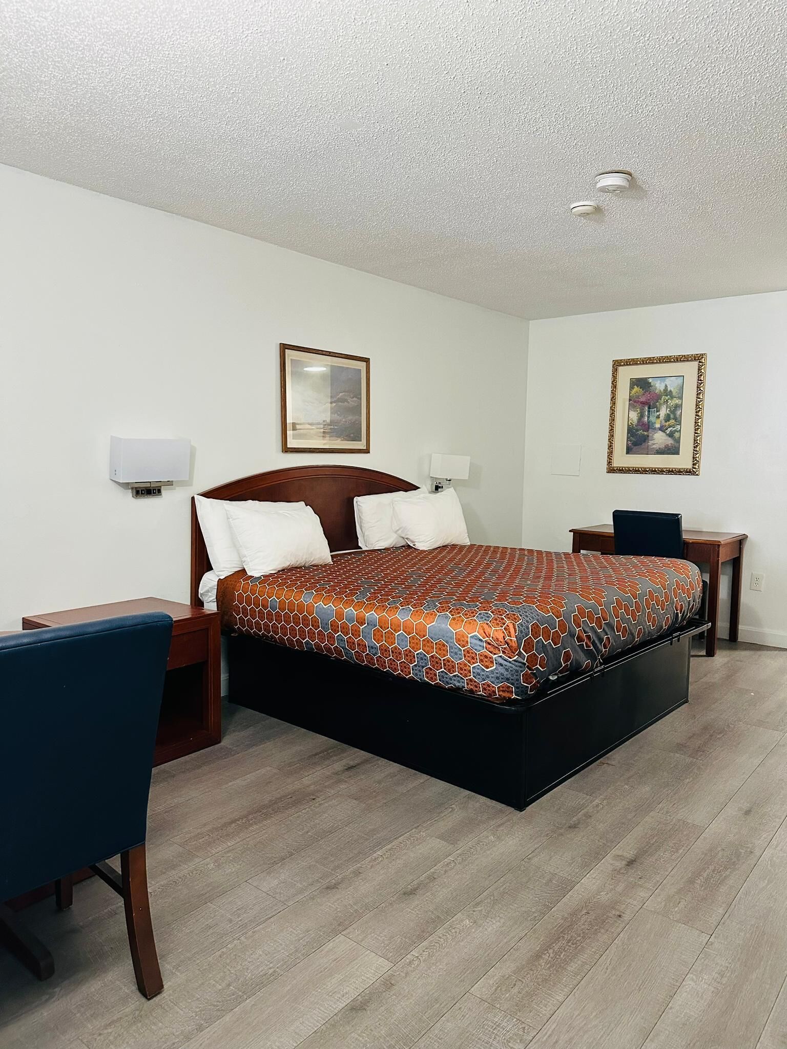 Una habitación de hotel con una cama grande, un escritorio, una silla y dos mesitas de noche.
