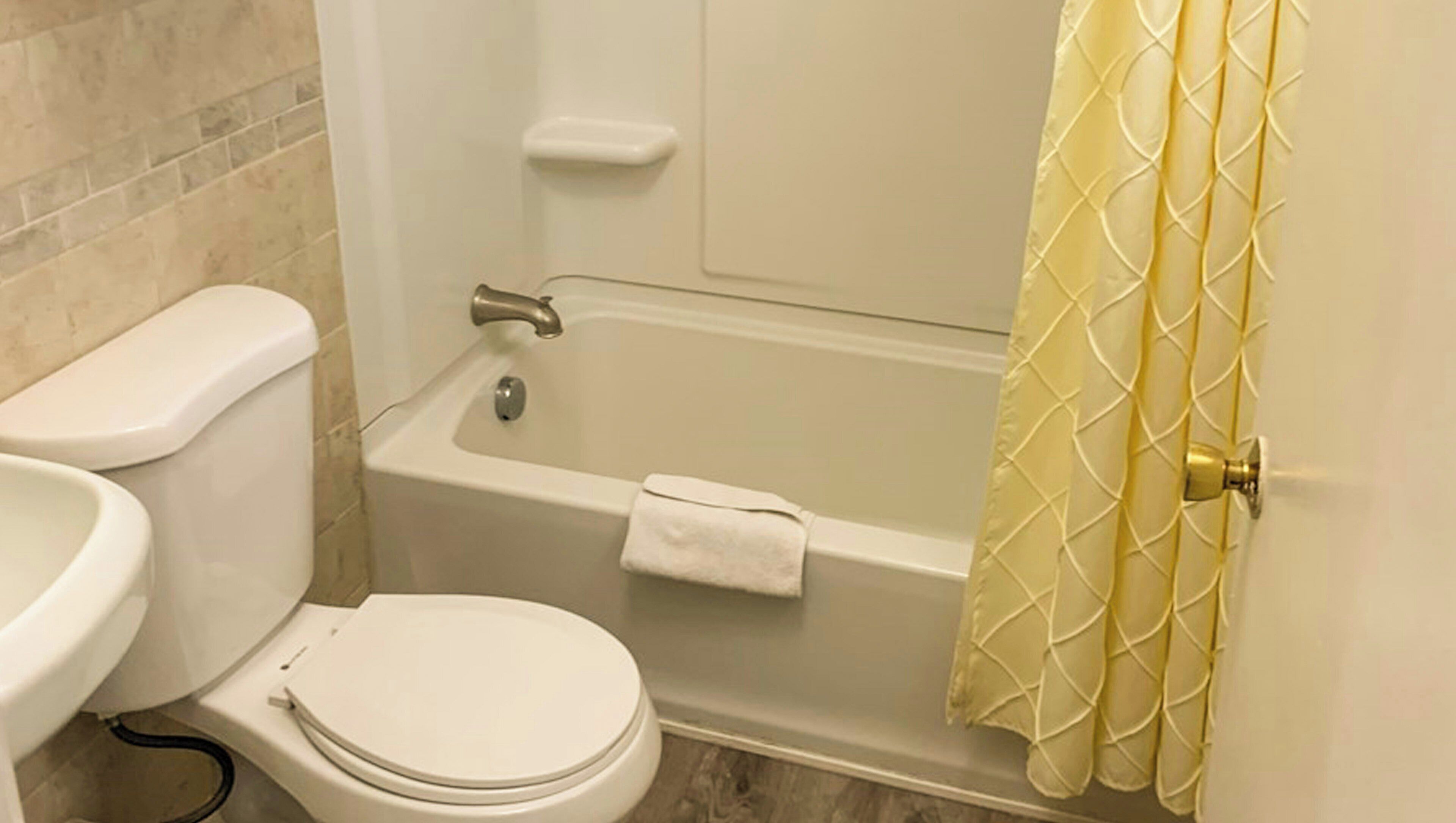 A bathroom with a toilet, sink, bathtub, and shower curtain.