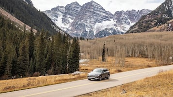 Une voiture circule sur une route, avec des montagnes en arrière-plan.