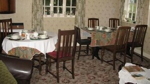 A dining room with a round table set for four, surrounded by wooden chairs. - Balterley Green Farm (Crewe)