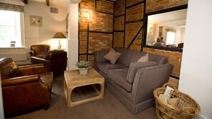 A cozy living room with a brown sofa, wooden coffee table, and wicker basket. - The Hawk Inn (Andover)