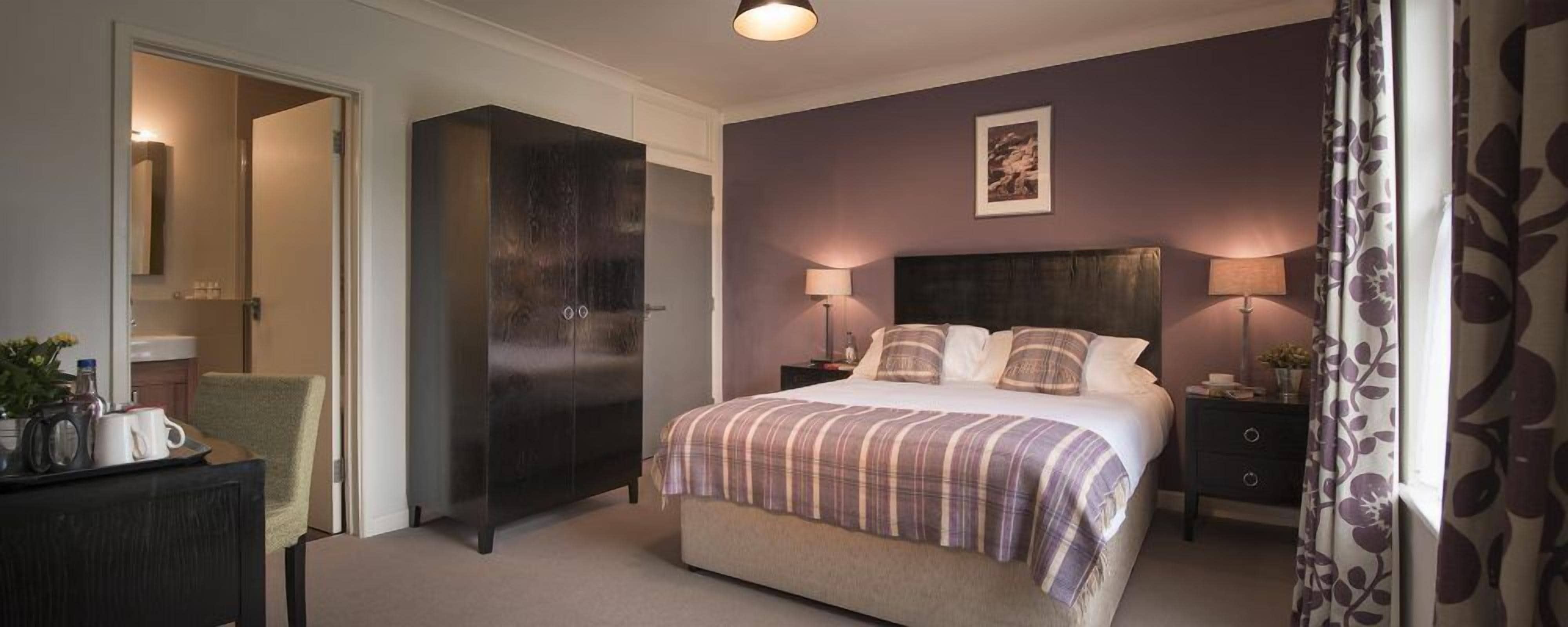 Un dormitorio con cama, mesitas de noche, cómoda y espejo.