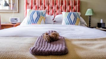 Una cama bien hecha con un cabecero a rayas, una manta de punto y almohadas decorativas.