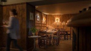A warmly lit dining area with wooden paneling and a table set for a meal. - The Hawk Inn (Andover)