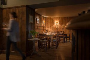 Comedor cálidamente iluminado con paneles de madera y una mesa dispuesta para una comida.