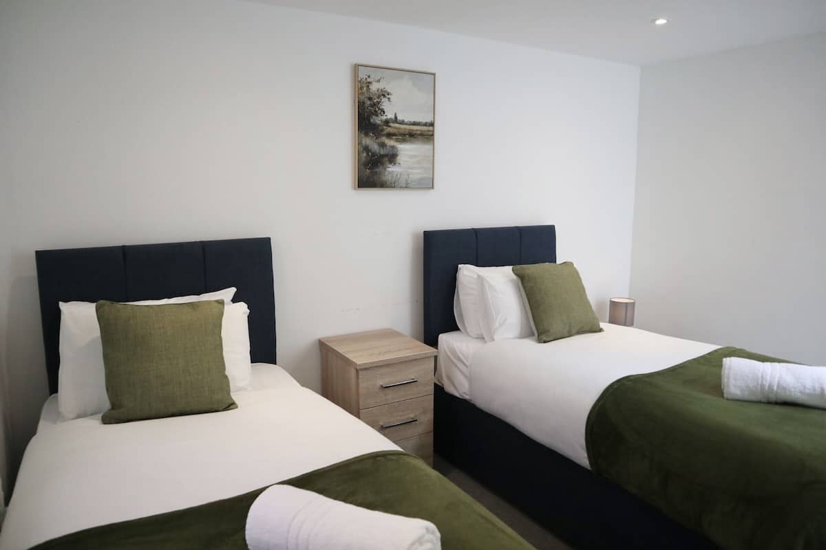 Two single beds with headboards, a small bedside table, and a wall-mounted picture.