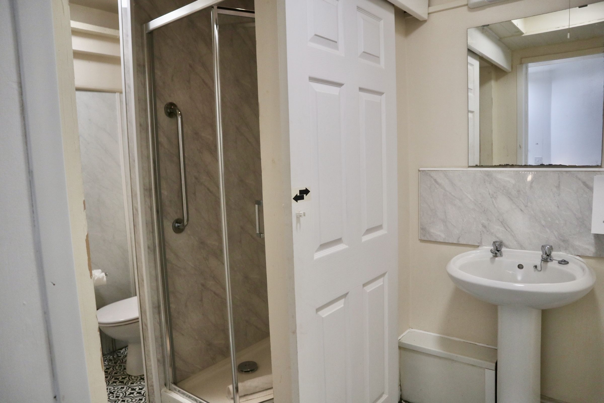 Un bagno con cabina doccia in vetro, un lavandino bianco e un water.