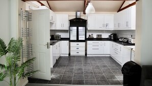 A kitchen with white cabinets, a black refrigerator, and a tiled floor. - City Centre Guest House - Gloucester Park (Gloucester)